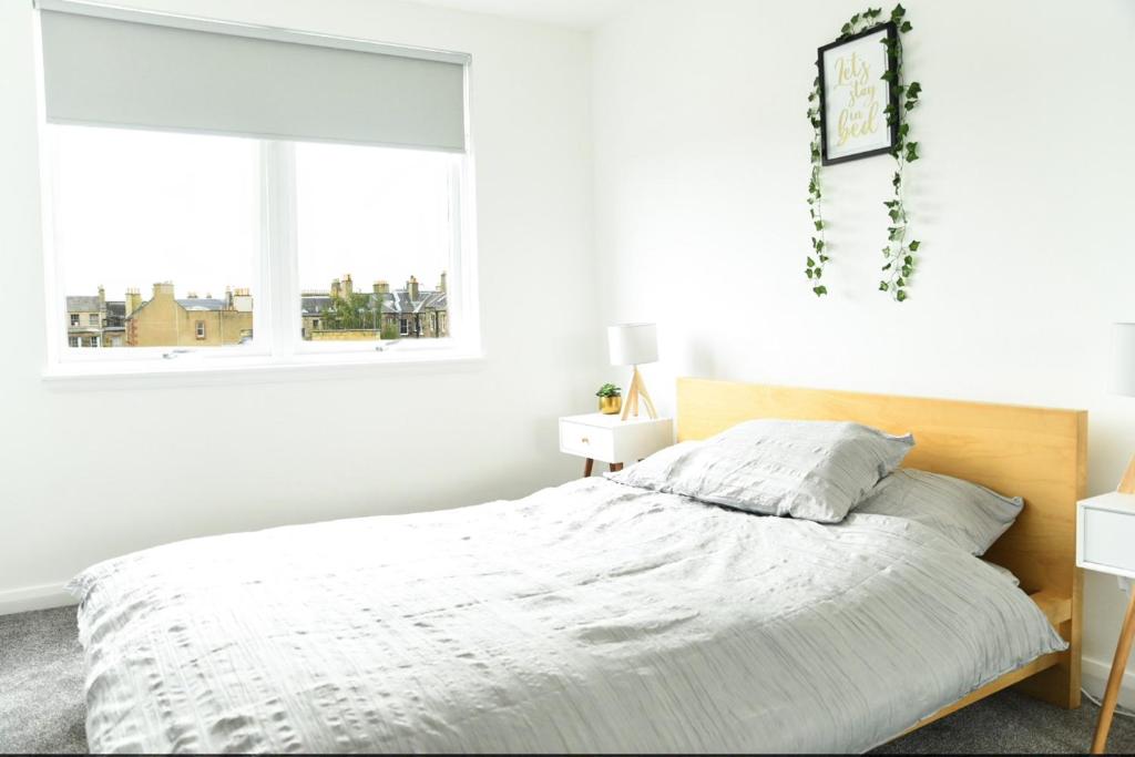 a white bedroom with a bed and a window at Fettes Hideaway in Edinburgh