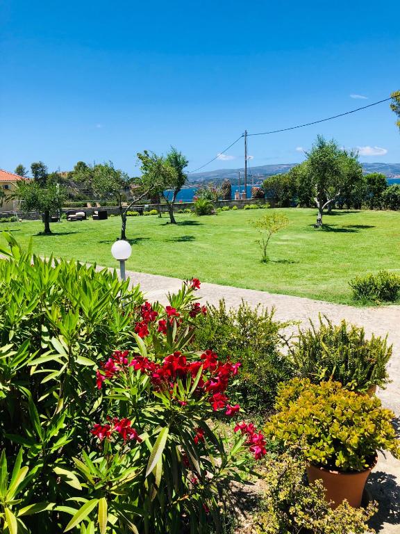 a park with red flowers and a field of grass at Aloni Studios and Apartments in Lassi