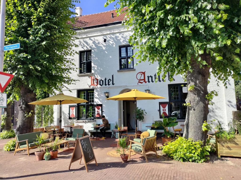 een restaurant met stoelen en parasols voor een gebouw bij Hotel Nieuw Antiek in Helden