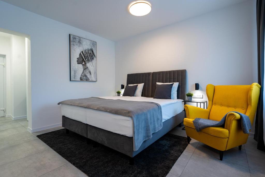 - une chambre avec un lit et une chaise jaune dans l'établissement Apartments & Room Forest, à Slunj