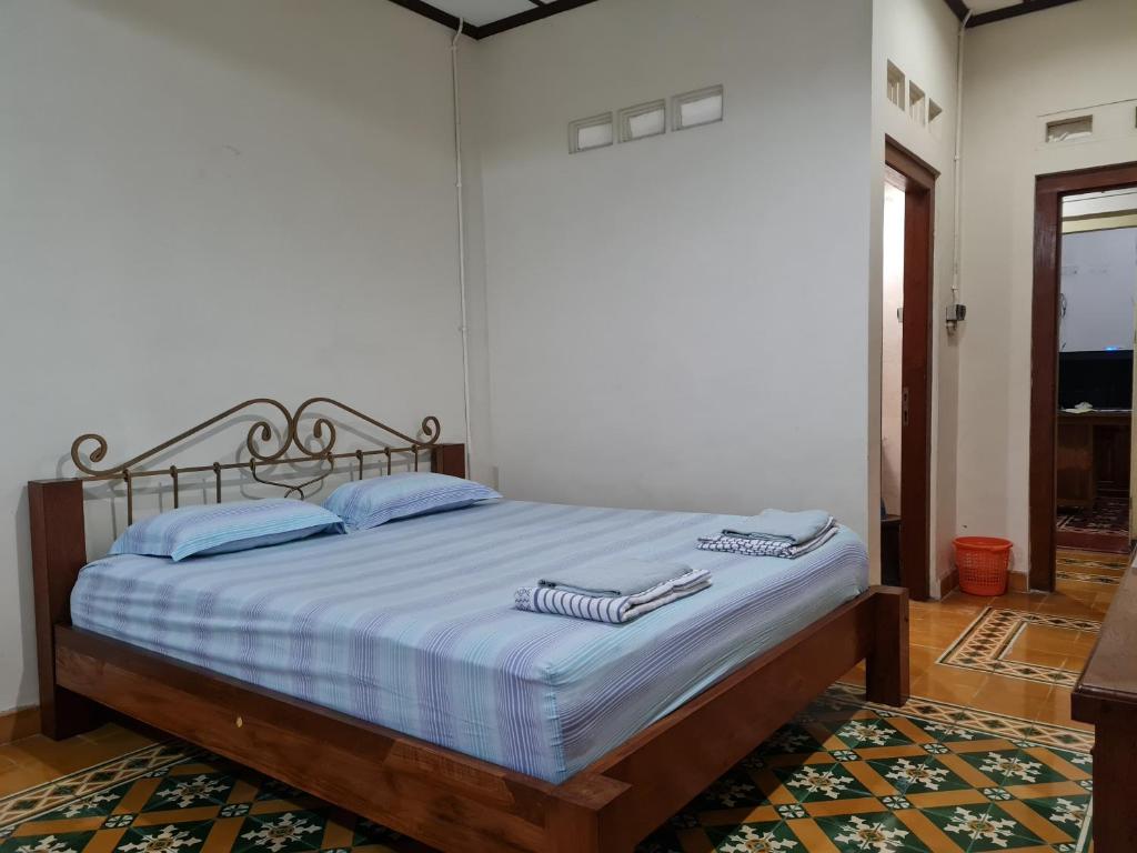 a bedroom with a bed with blue and white sheets at Omah Pitoe Yogya Homestay in Yogyakarta