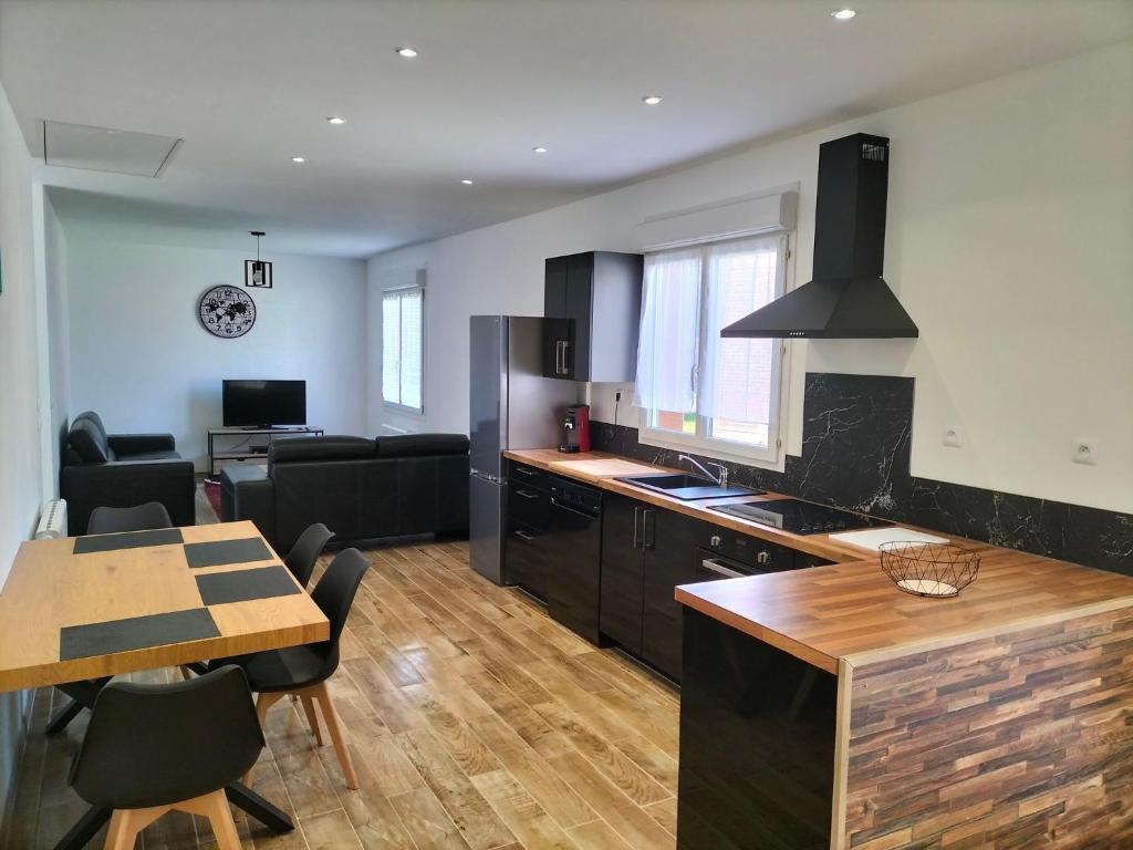 een keuken en een woonkamer met een tafel en een eetkamer bij Maison plain pied 4 personnes parking gratuit in Vendeville