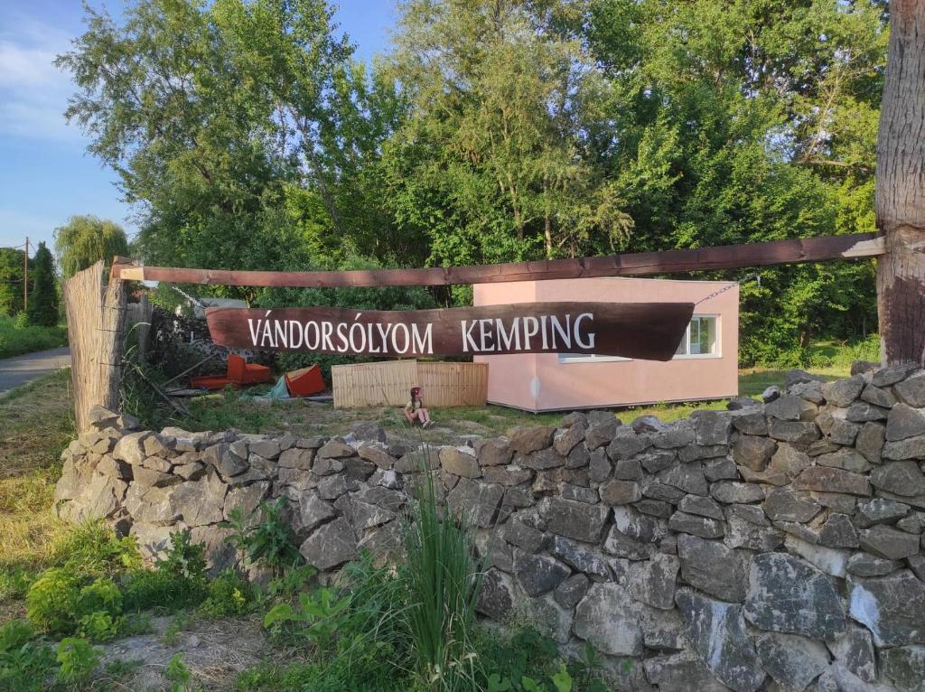 a sign for a park with a stone wall at Vándorsólyom kemping in Nagymaros