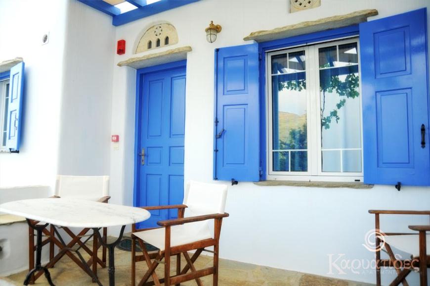 een patio met blauwe deuren en een tafel en stoelen bij Karyatides Apartments in Kariá