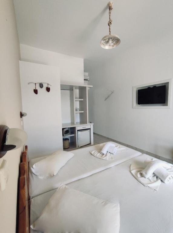a white room with two beds and a tv at Hotel Aegeon in Mylopotas