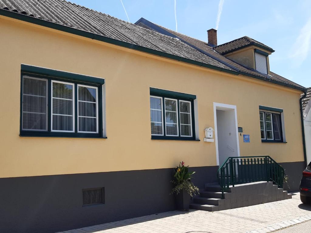 a yellow house with black windows and stairs at Ferienzimmer LANG in Apetlon