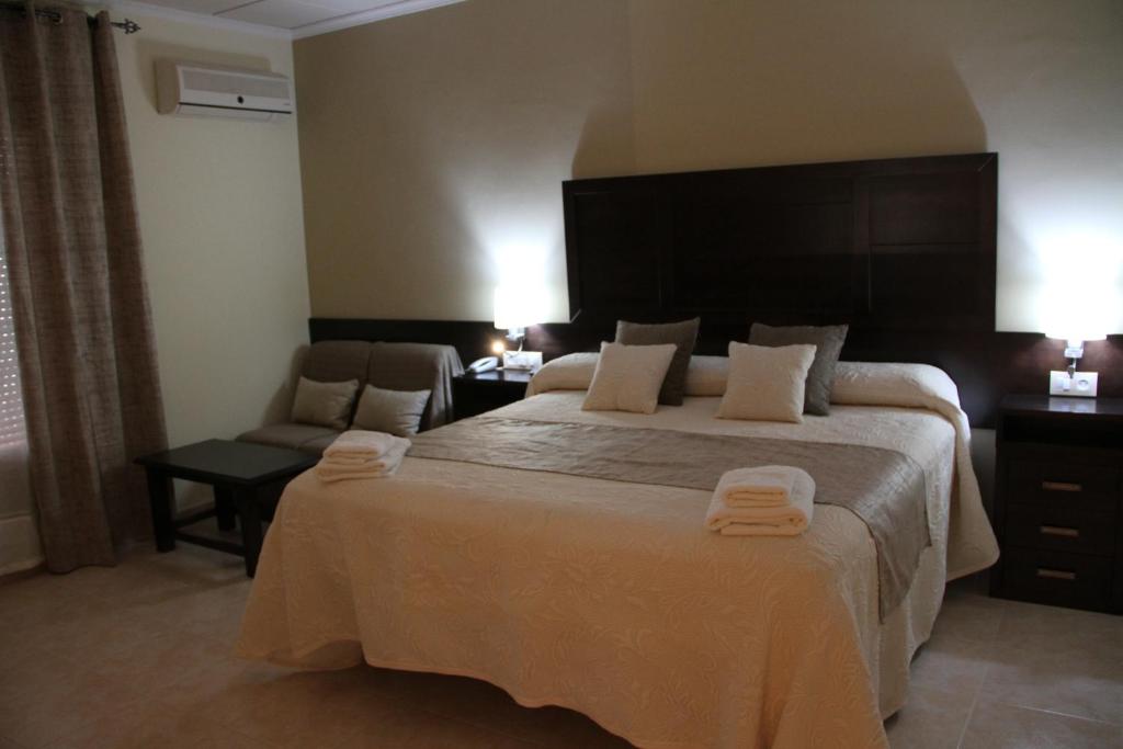 a hotel room with a large bed and a chair at Hotel Don Juan in Puente de Génave