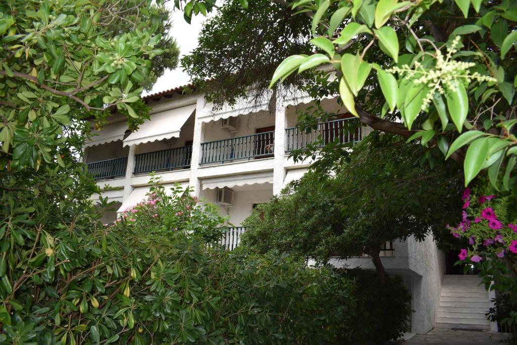 a white building with balconies and trees at Alexander in Pefkochori