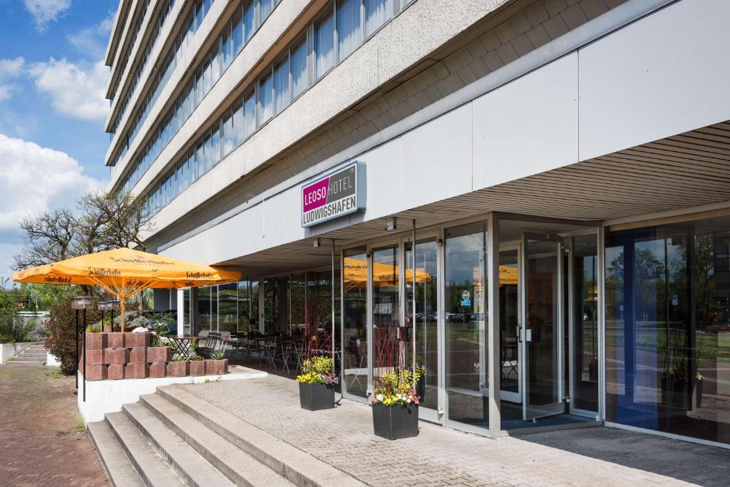 ein Gebäude mit einem Regenschirm und Bänken davor in der Unterkunft Leoso Hotel Ludwigshafen in Ludwigshafen am Rhein