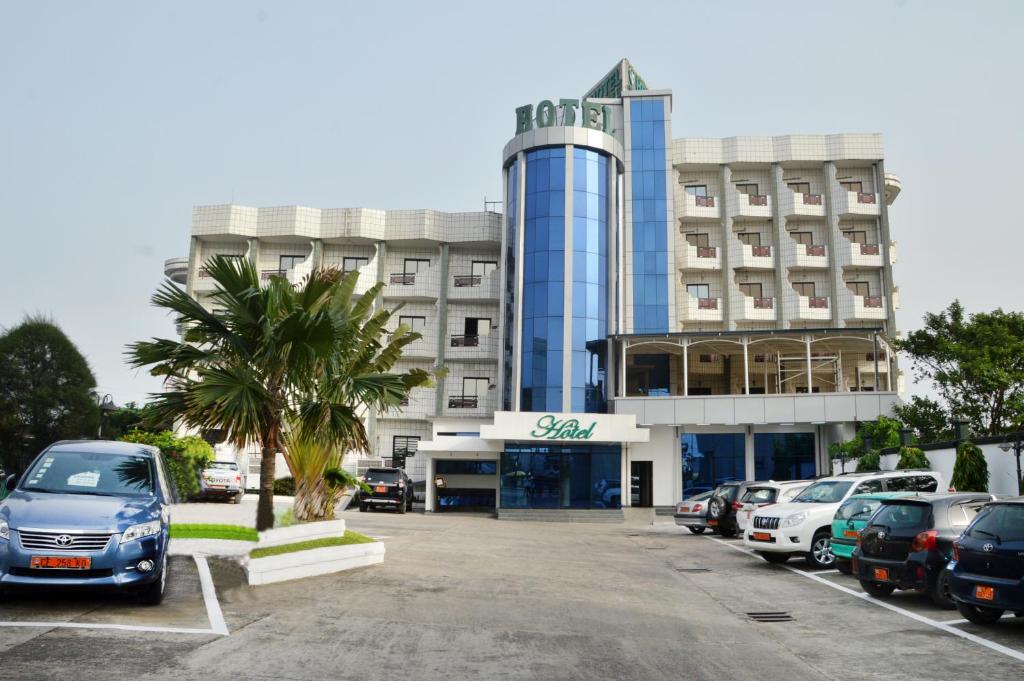 a building with cars parked in a parking lot at Hotel Vallée Des Princes in Douala