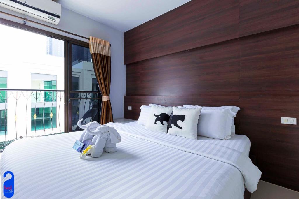 Bed By City Hotel في بانكوك: اثنين من الحيوانات المحشوة جالسين على سرير في غرفة النوم