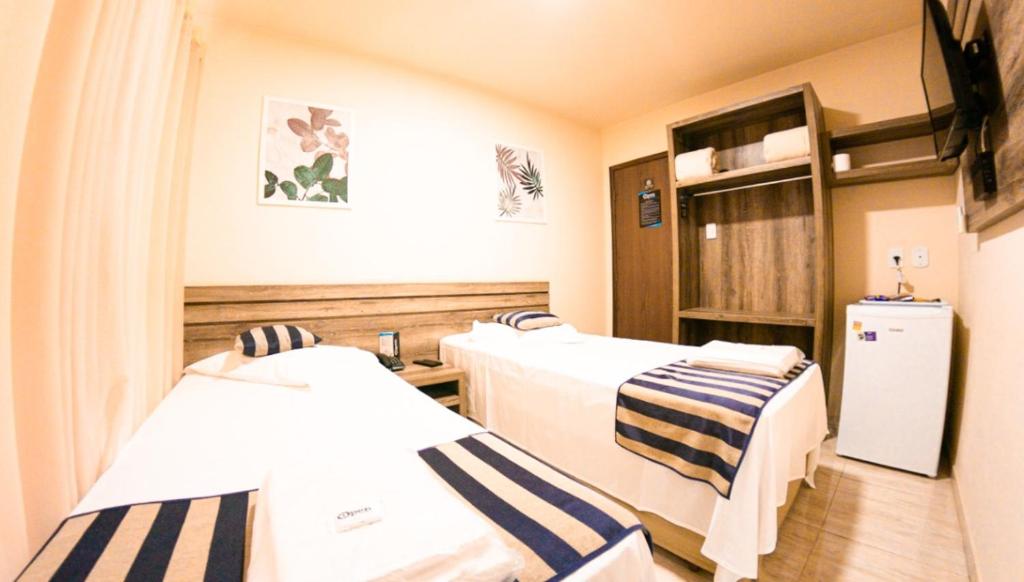 a hospital room with two beds and a refrigerator at Open Hotel in Telêmaco Borba