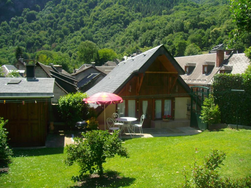 dom ze stołem i parasolem na dziedzińcu w obiekcie petite maison de montagne avec jardin w mieście Cier-de-Luchon