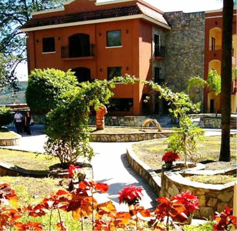 a building with a garden with flowers in front of it at Hotel Hacienda Cola del Caballo in Santiago