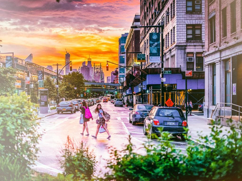 two people walking down a city street with cars at Q4 Hotel and Hostel in Queens