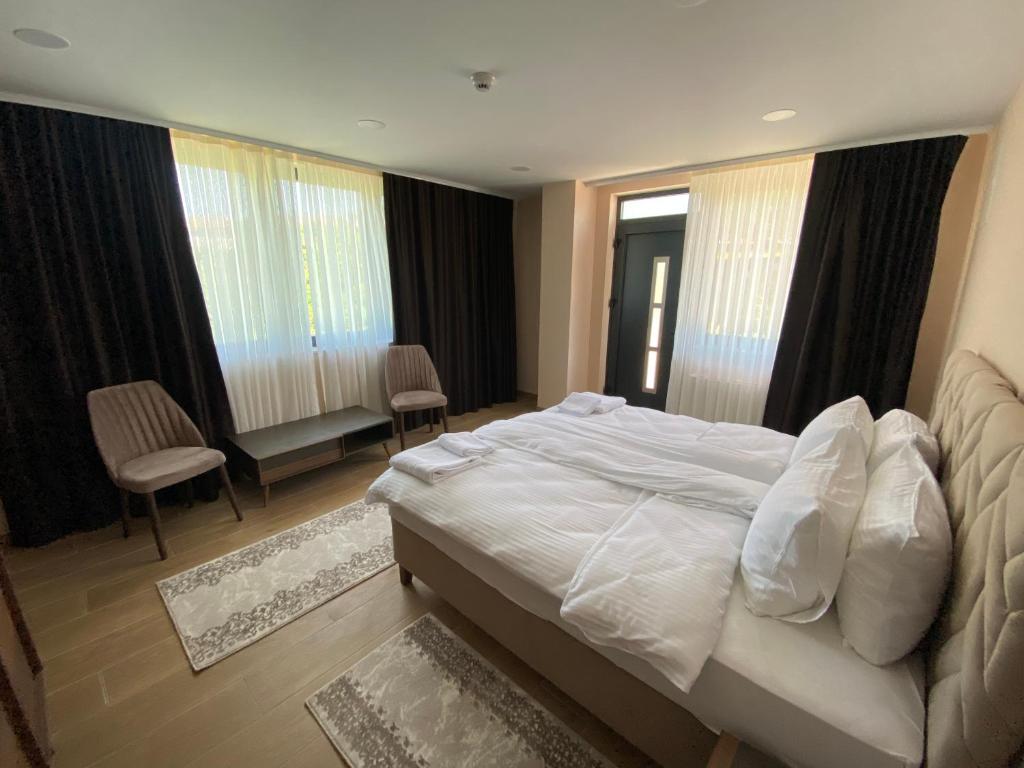 a bedroom with a large bed and two windows at Apartmani Nešković Foča in Foča