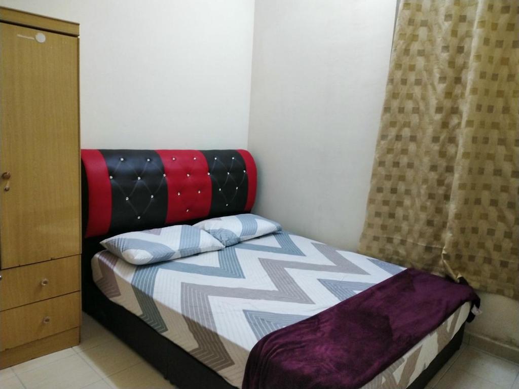 Dormitorio pequeño con cama con almohadas en Homestay Kuala Terengganu near Batu Burok, Hospital HSNZ, KTCC Mall, Drawbridge C, en Kuala Terengganu