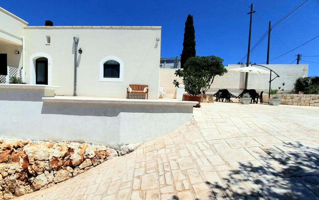 een wit gebouw met een stenen muur en een patio bij I Due Carrubi in Ostuni