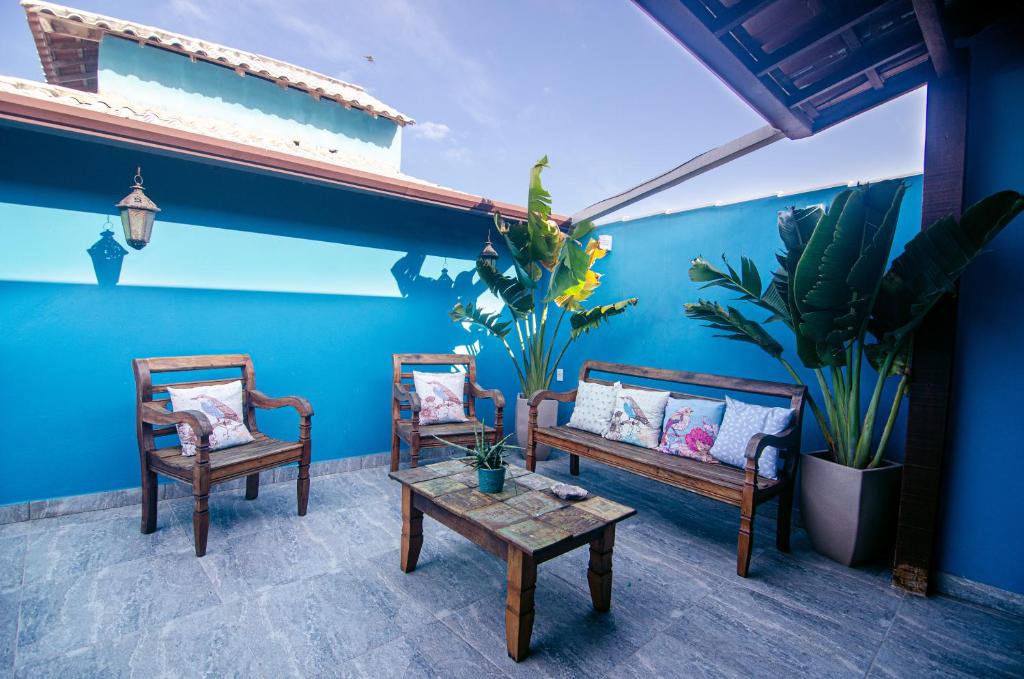a patio with two chairs and a table and a blue wall at Búzios Conforto Guest House in Búzios