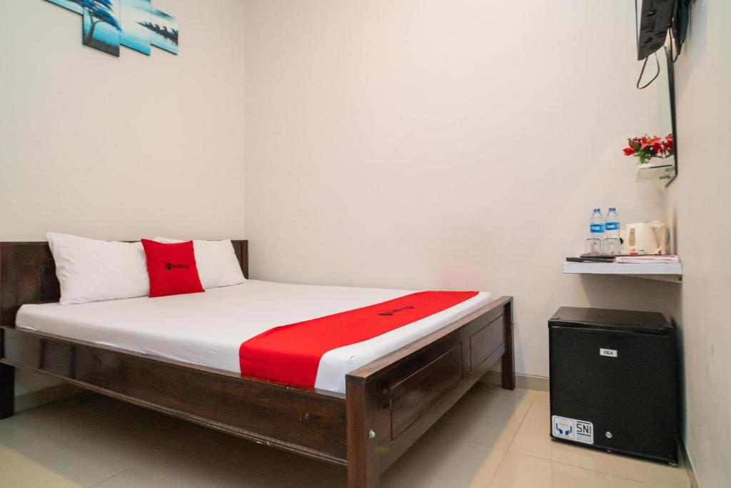 a bed in a room with a red and white mattress at RedDoorz Plus At Merr Rungkut Jl Gunung Anyar in Gununganjar