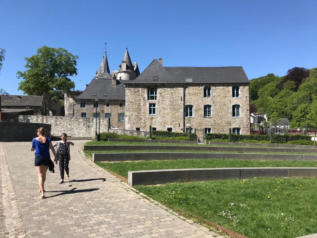 une femme et un enfant marchant devant un château dans l'établissement Residence des Recollets Apartments, à Durbuy