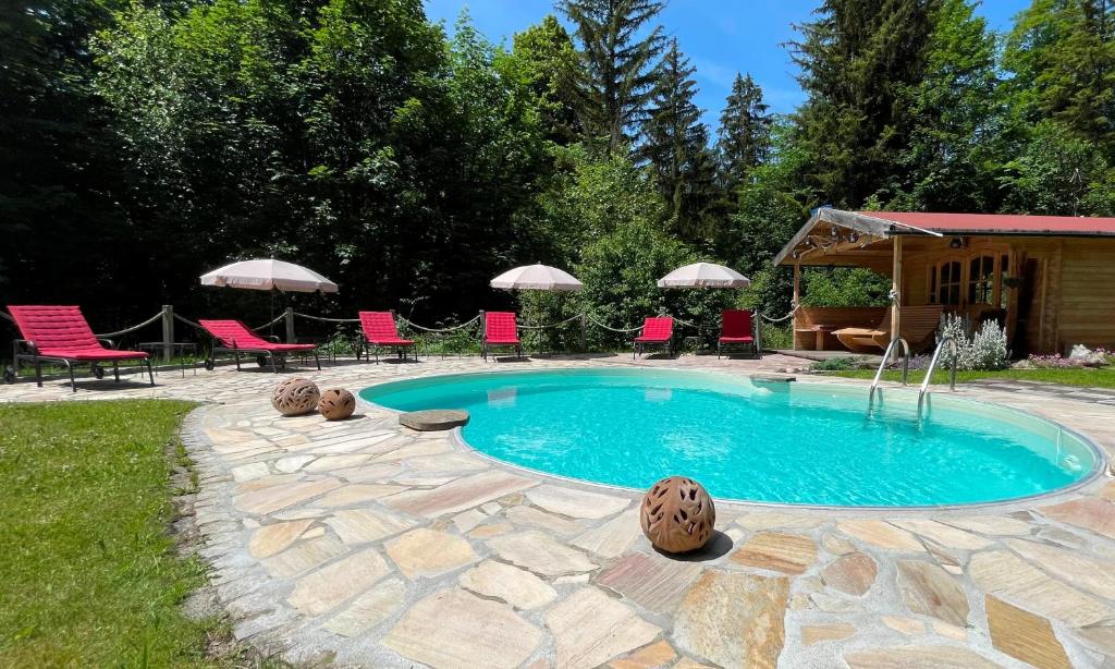 a swimming pool with chairs and umbrellas in a yard at Landhaus Gastager in Ruhpolding