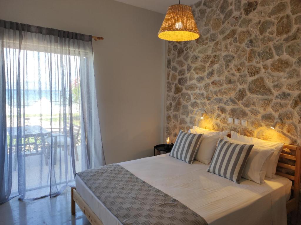 a bedroom with a large bed and a stone wall at Thalassa Apartments & Studios in Kavos