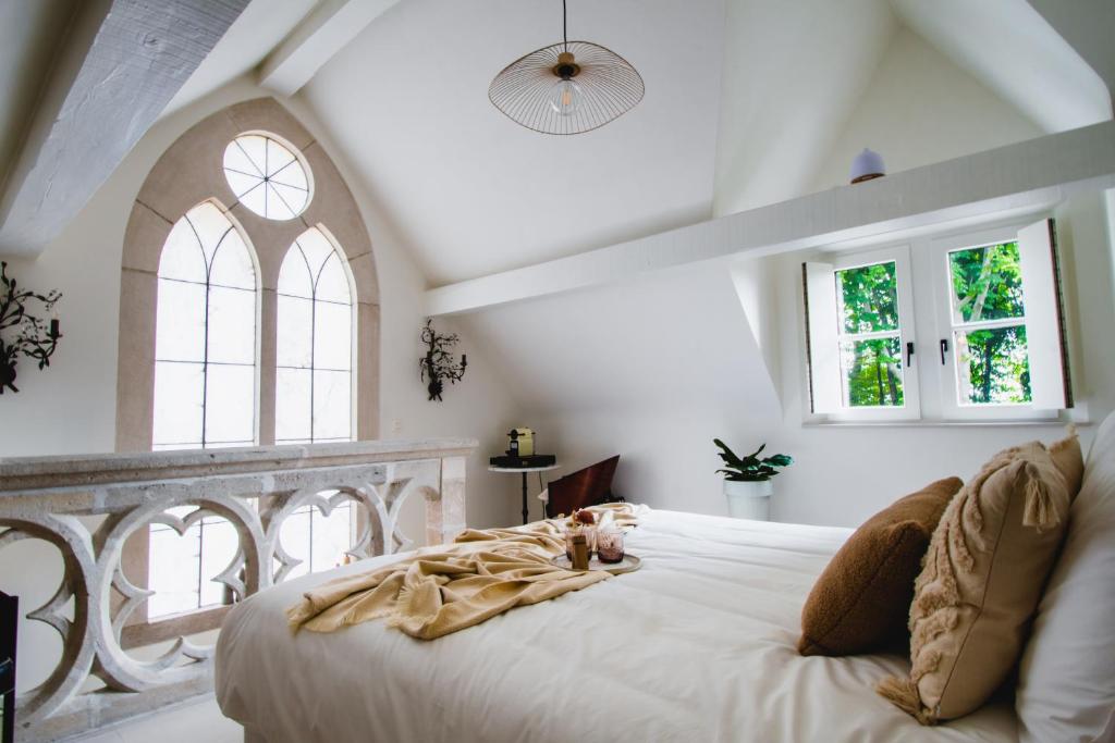 una camera da letto con un grande letto bianco e finestre di B&b kleinen bosch a Beveren