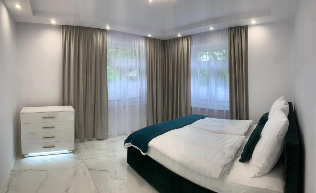 sypialnia z łóżkiem, komodą i oknami w obiekcie Apartament Latarników Stilo w Sasinie