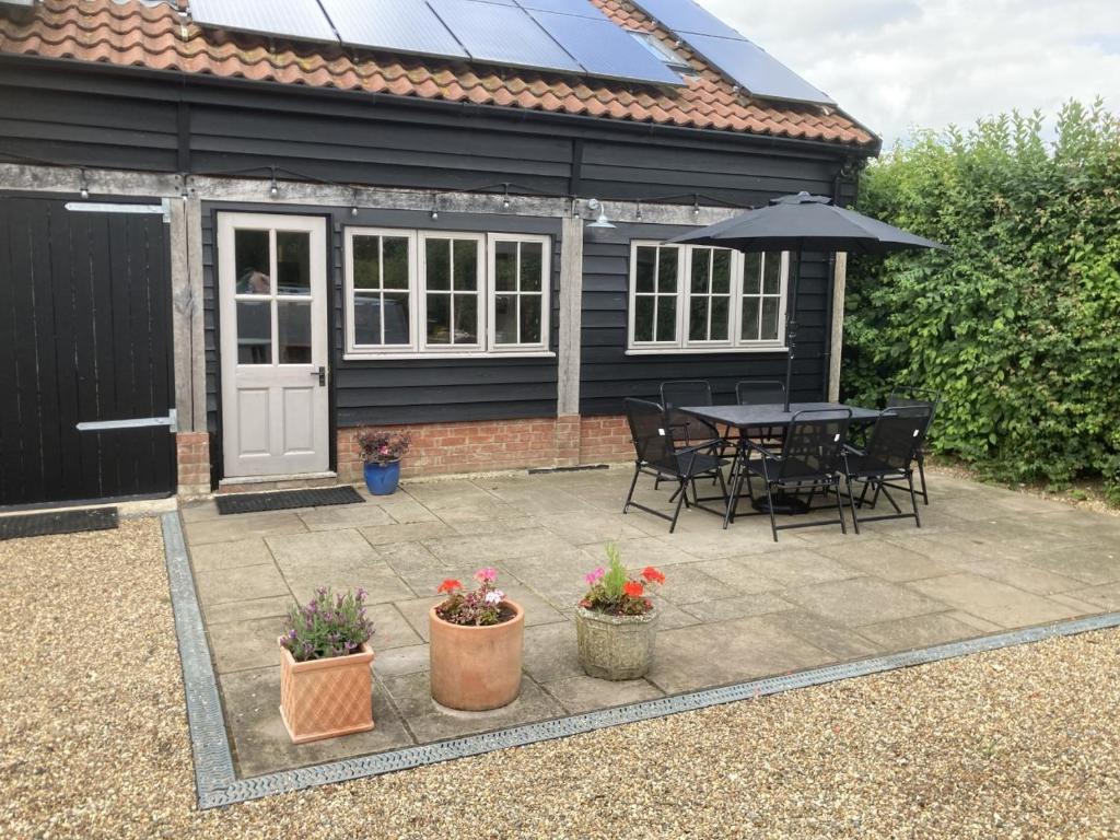 a patio with a table and chairs and an umbrella at The Shed in Long Stratton