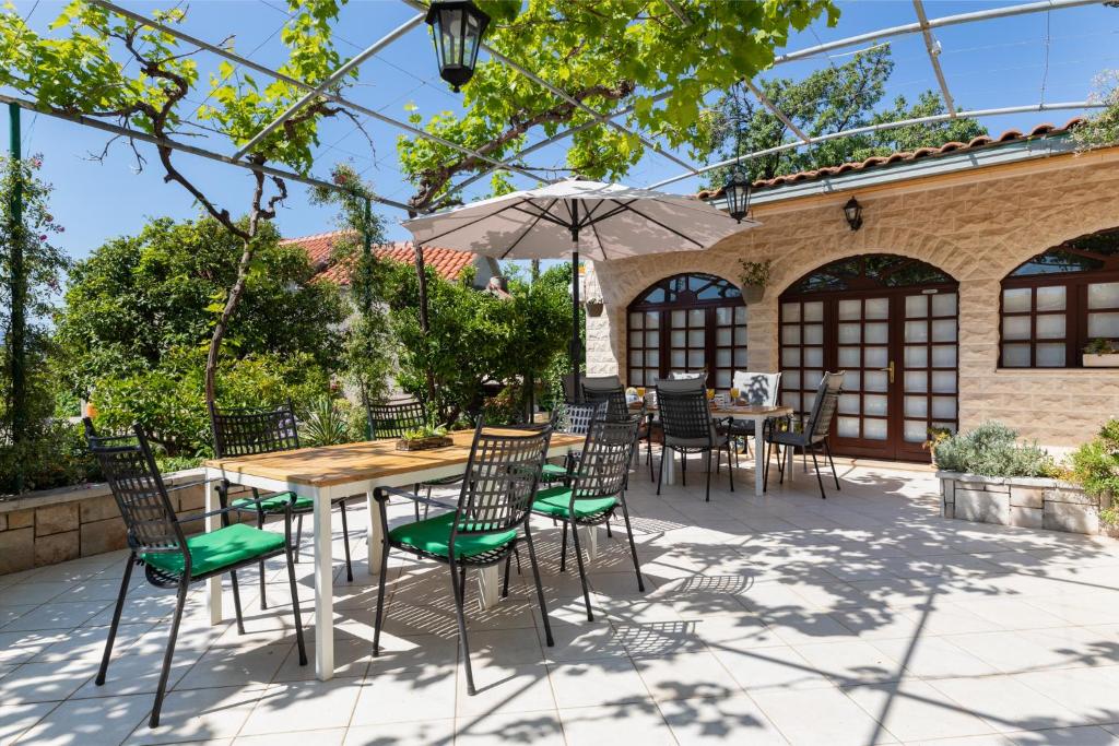 un patio con mesa, sillas y sombrilla en Apartments Paloc - Blue en Bol