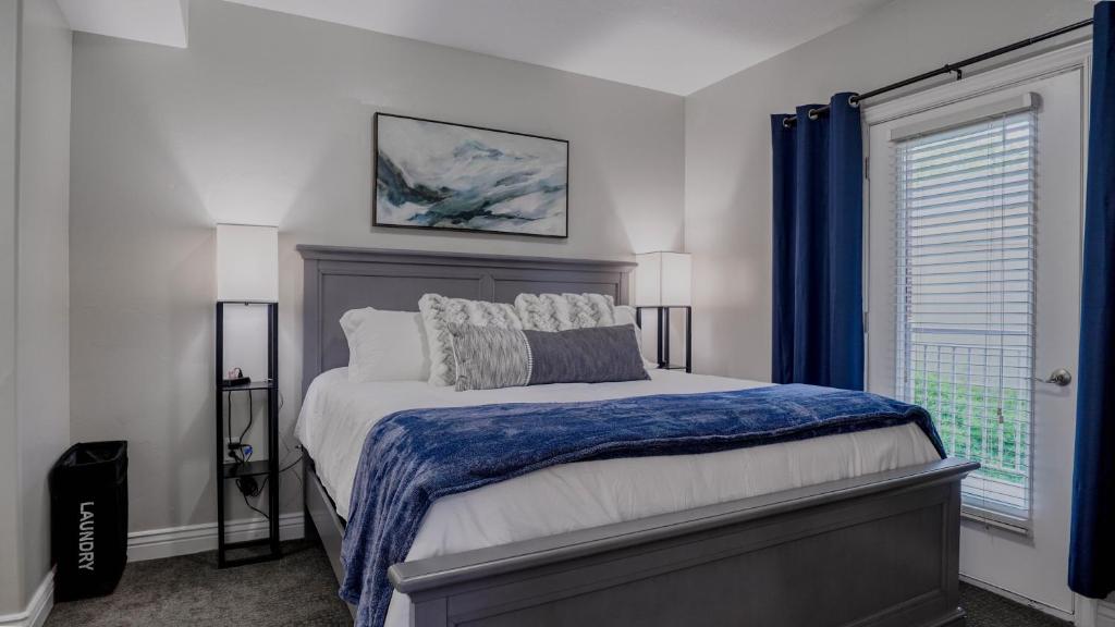 a bedroom with a bed with a blue blanket and a window at Downtown, KING Bed, Fast WiFi! in Salt Lake City