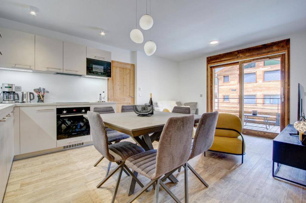 une cuisine et une salle à manger avec une table et des chaises dans l'établissement Carlina 203, à Morzine