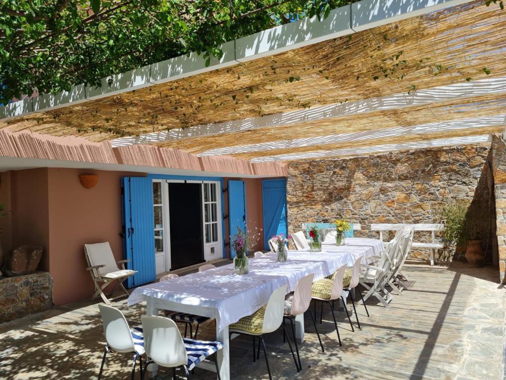 una mesa larga con mesas blancas y sillas bajo una pared de ladrillo en Villa-Agave , by the sea in Porto-Rafti outside Athens, en Porto Rafti