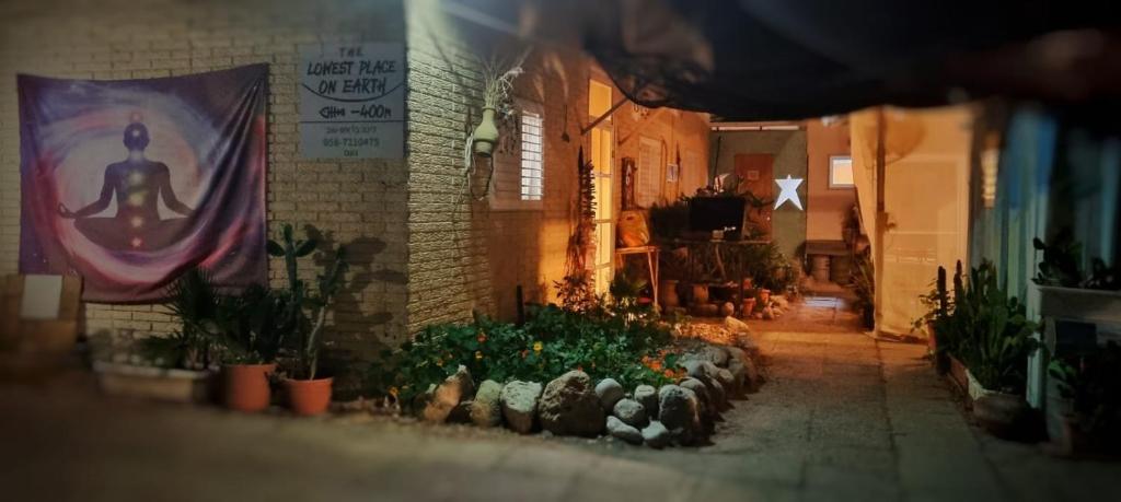 an alley with plants and a sign on a building at The Lowest Place on Earth B&B in Neʼot HaKikar