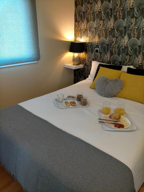 a bed with two plates of food on it at Naturalayos I y Naturalayos II - casas para parejas - jacuzzi in Pelayos de la Presa