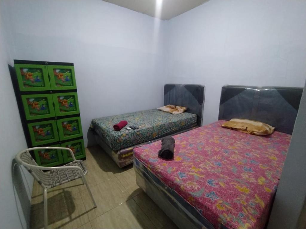 ein Zimmer mit 2 Betten und einem Stuhl darin in der Unterkunft Hotel Near Ramayana 3 in Pekalongan