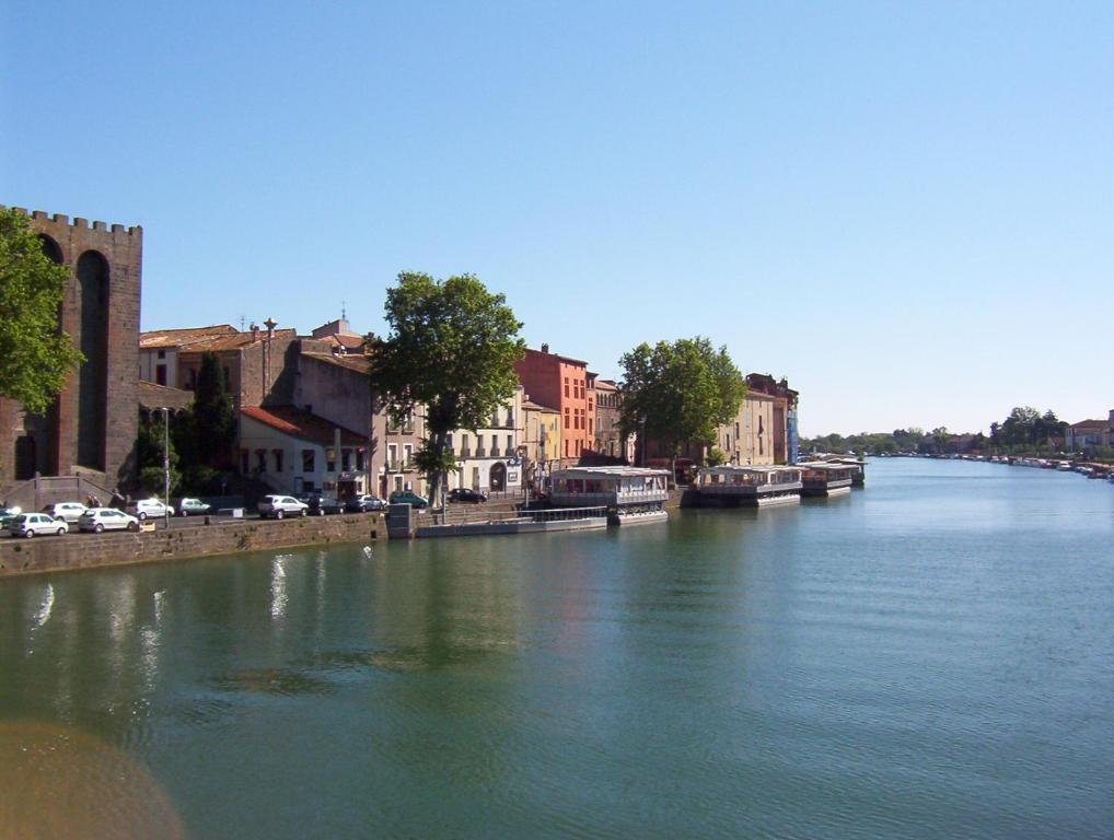 a river with buildings and cars on the side at 3 bedroom apartment overlooking river in Agde