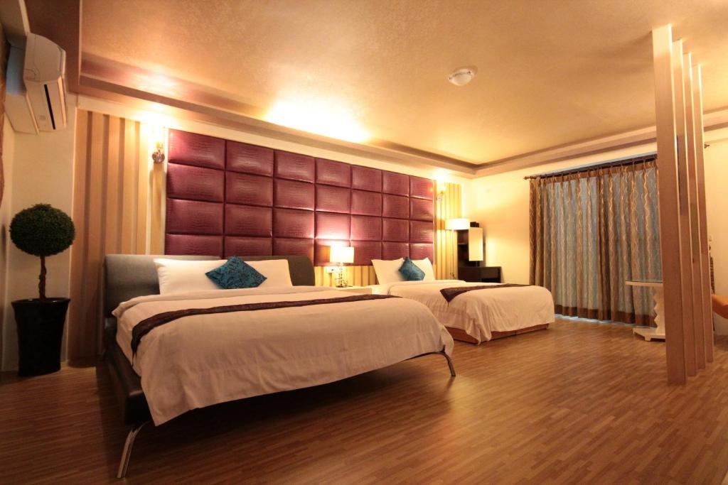 a hotel room with two beds and a large headboard at Yudo B&amp;B Yilan in Dongshan