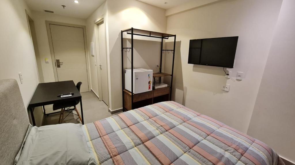 ein Schlafzimmer mit einem Bett, einem Schreibtisch und einem Fernseher in der Unterkunft Flat encantador América Campos in Campos dos Goytacazes