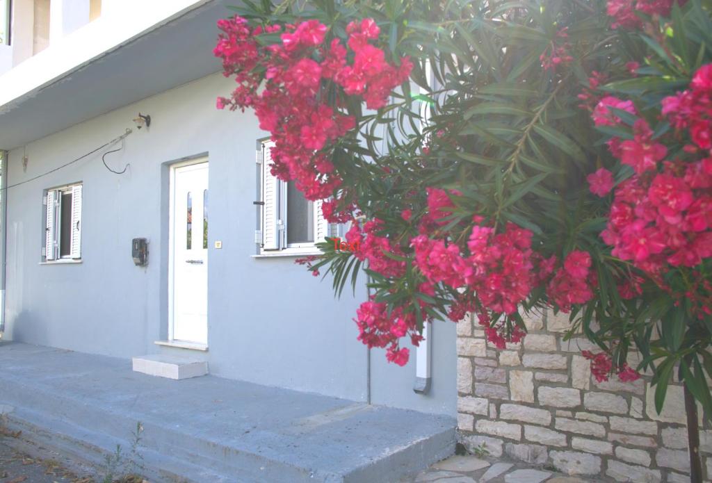 Um edifício com flores cor-de-rosa à frente. em Antonia's Rustic Retreat em Dhórion