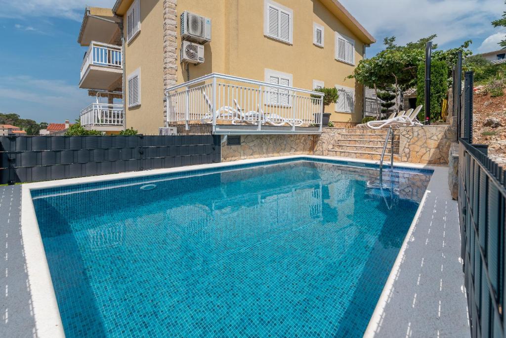 a swimming pool in front of a house at Apartments Kapetan in Trogir