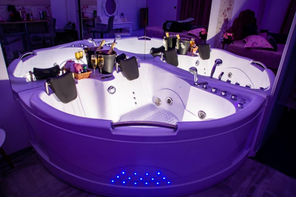 Una bañera en una habitación púrpura con botellas. en Pink Boutique, en Campina