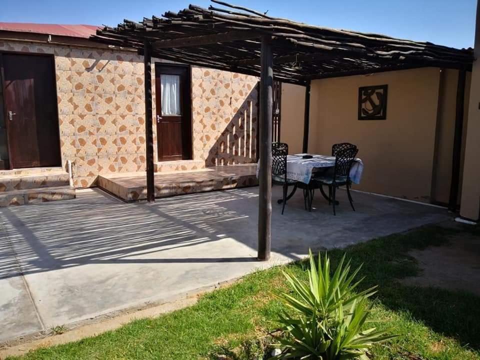 a patio with a table and chairs under a pergola at Namibia Skipper Services in Walvis Bay