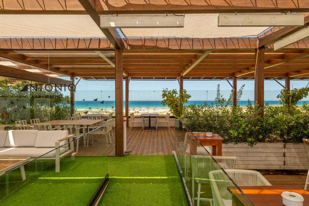 an outdoor patio with tables and chairs and the beach at Hotel Antonio II in Zahara de los Atunes