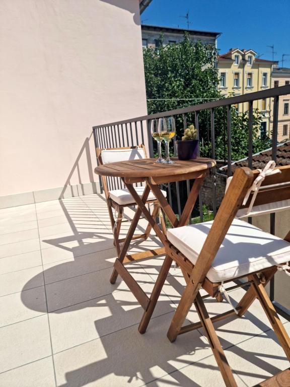 a wooden table and chair on a balcony with wine glasses at Central Studio Apartment in Pula