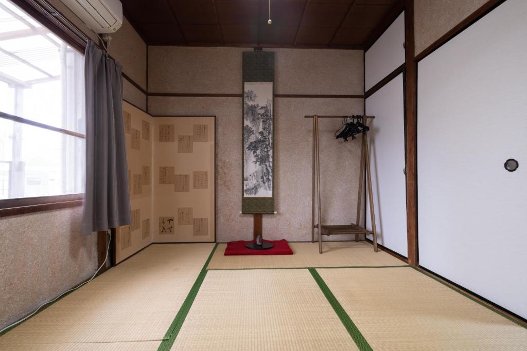 an empty room with a painting on the wall and a window at Ikkenya Tsushima in Okayama