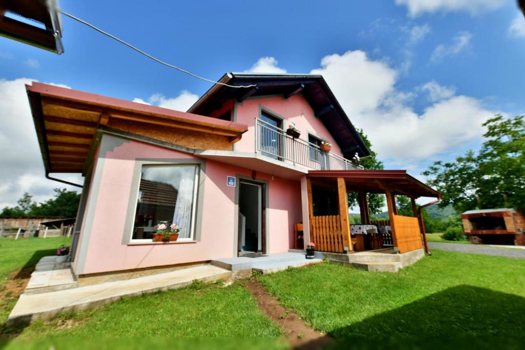 ein kleines rosafarbenes Haus mit einem grünen Hof in der Unterkunft Natura hause in Rakovica