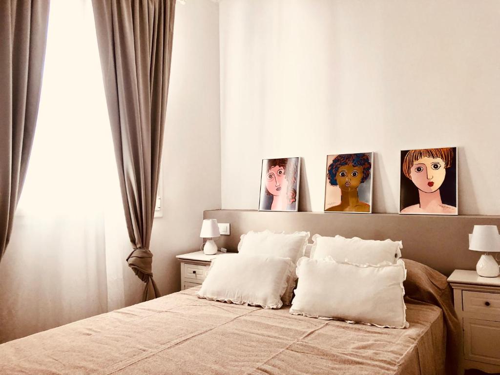 a bedroom with a bed with four portraits on the wall at Precioso piso en el centro neurálgico de Olot in Olot