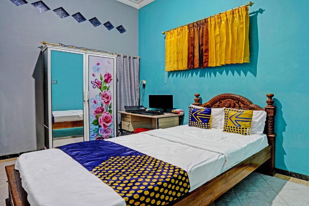een slaapkamer met een bed en een bureau met een computer bij OYO Homes 91142 Desa Wisata Alam Gosari (wagos) 